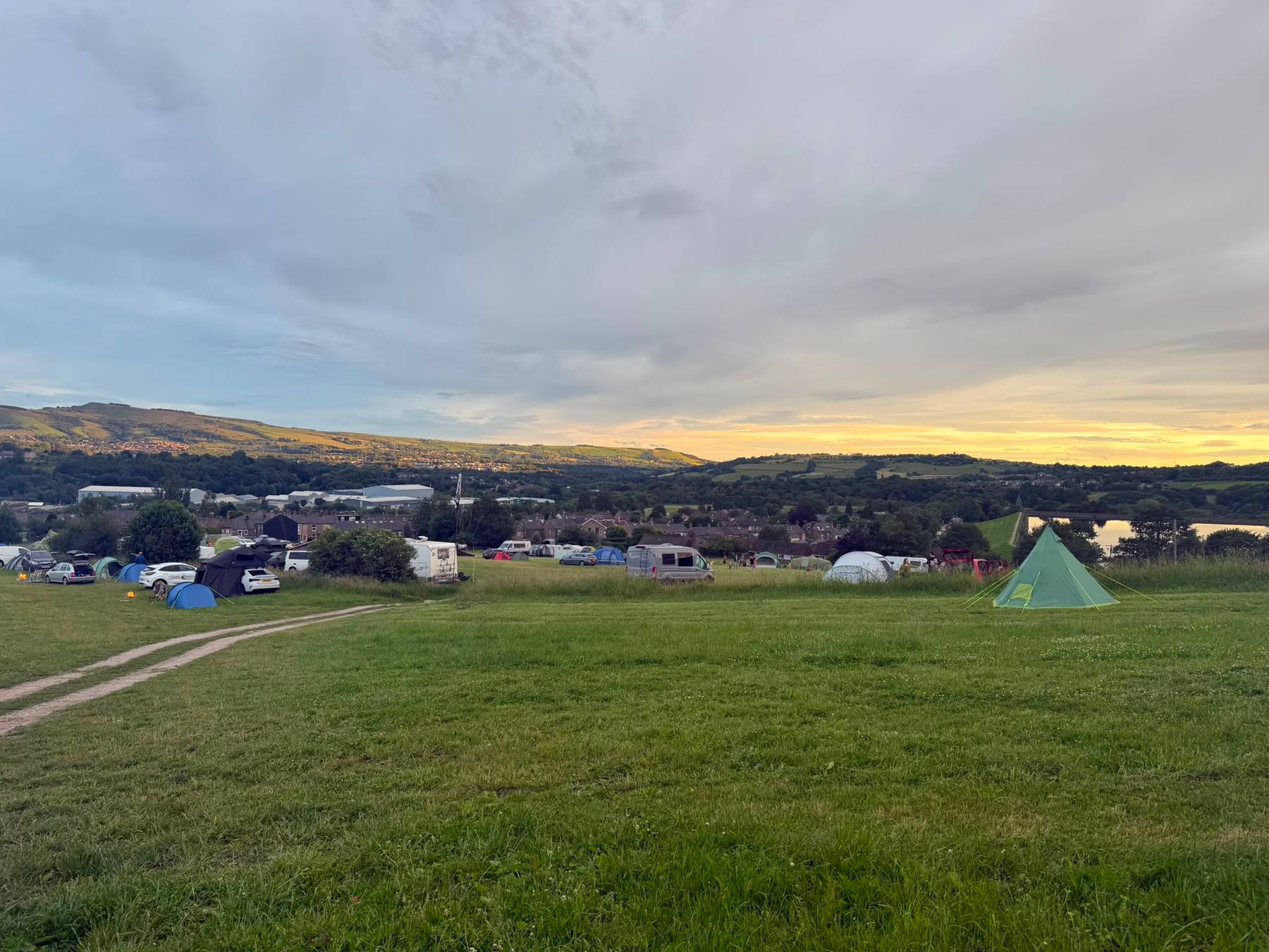 Tents pitched on the camping field at sunset overlooking the valley